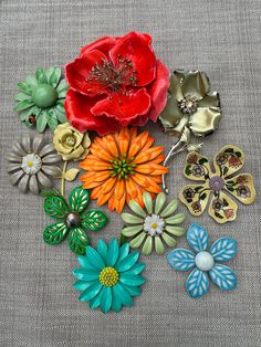 a bunch of flowers that are sitting on a table cloth with some brooches