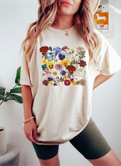 Floral Shirt Cottagecore, Wildflower Shirt, Boho Flower Shirt, Cottagecore Tshirt/Cottagecore Shirt/Pressed Flowers/Flower Garden Lover Gift Crafted from lightweight cotton that is perfect for active wear or leisure, our pressed floral shirt offers comfort and vintage style. It's perfect for casual wear, whether going to work, grabbing coffee with friends, or just wanting to wear a comfortable shirt during daily activities. Whether you're curled up on the couch, hanging out with your family, or Casual Multicolor Tops With Floral Patchwork, Casual Multicolor Floral Patchwork Tops, Multicolor Crew Neck Shirt With Plant Print, Multicolor Graphic Tee With Floral Print, Casual White Tops With Floral Patchwork, Multicolor Floral Graphic Tee Shirt, Multicolor Floral Print Graphic Tee Shirt, Multicolor Floral Print Graphic Tee, Casual Short Sleeve Top With Floral Patchwork