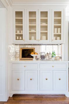 a kitchen with white cabinets and gold knobs on the cupboard doors is seen in this image