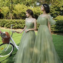 two women in green dresses standing next to a bicycle