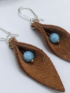 two blue beads are attached to brown leather leaves