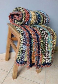 a multicolored blanket sitting on top of a wooden stool