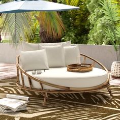 an outdoor daybed with pillows and umbrellas on the ground next to palm trees