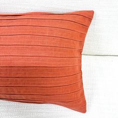 an orange pillow sitting on top of a white couch