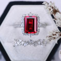 an engagement ring with a red stone surrounded by diamonds