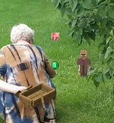 an older woman sitting on the grass holding a wooden box in front of her face