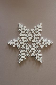 a snowflake made out of white beads on a brown surface with no background