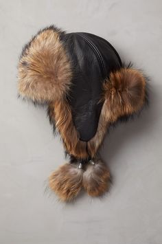 Embrace winter's rustic charm—and elevate your style—with this fur-trimmed hat. This luxurious trapper pairs buffed lambskin leather with fine fur that's showcased along every edge. But make no mistake, this show-stopping style was designed to hold out the cold; whether you're exploring the big city or out on the slopes, fur-lined earflaps, chin ties with fur poms, and a fitted elastic fur-trimmed nape will keep you plenty warm. This one-of-a-kind cap makes for a great winter—and a great gift. L Furr Hat, Western Hat Styles, Cowboy Hat Styles, Fur Keychain, Alt Clothes, Cowhide Pillows, The Aviator, Aviator Hat, Trim Styles