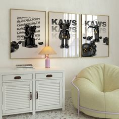 two framed pictures hang on the wall above a white cabinet and side table with a lamp