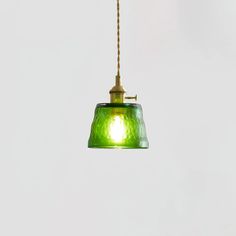 a green glass light hanging from a gold colored chain on a white wall and ceiling