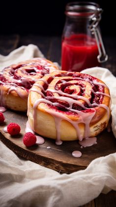 raspberry cinnamon rolls with icing on a cutting board next to a jar of juice