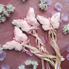 some pink and white flowers are laying on a purple table cloth with ribbons in the shape of butterflies