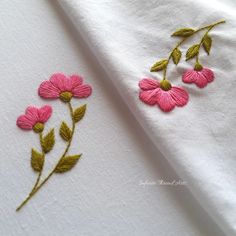 pink flowers are embroidered onto white linens