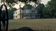 a large white house sitting on top of a lush green field next to a tree