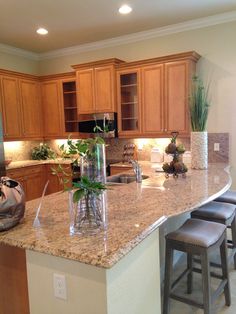 a kitchen island with two stools in front of it and plants on the counter