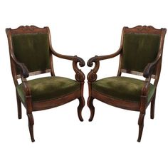 a pair of carved wood chairs with green velvet upholstered back and armrests