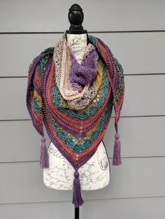 a multicolored shawl with tassels on top of a mannequin