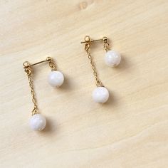 With an eye-catching and dainty design, these 18k gold-filled string earrings feature a beautiful rainbow moonstone beads on 18k gold filled studs. These earrings are double sided, with 8mm moonstone beads dropping from the front and back.  The entire earring is about 1 inch long. *18k gold filled post * Rainbow moonstone * Earrings are 1 inch long * Non-tarnishing and waterproof About moonstone: Moonstone is a captivating gemstone renowned for its ethereal, iridescent sheen that resembles the soft glow of the moon. It is revered for its metaphysical properties, believed to promote inner growth, intuition, and harmony. This gem is also cherished for its perceived ability to alleviate stress and stabilize emotions, making it a popular choice for those seeking emotional balance and tranquili White Long Drop Pearl Earrings In 14k Gold Filled, White Long Drop Pearl Earrings In 14k Gold, White Moonstone Earrings For Daily Wear, White Gold Plated Dangle Pearl Earrings, Minimalist White Gold Plated Pearl Earrings, Minimalist White Gold-plated Pearl Earrings, White Gold-plated Dangle Pearl Earrings, White Gold Plated Minimalist Pearl Earrings, 14k Gold Filled White Pearl Drop Linear Earrings