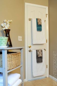 towels are hanging on the towel rack in front of an open door with a basket next to it