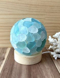 a blue glass ball sitting on top of a wooden table next to a white flower