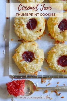 coconut jam thumbnut cookies on a baking sheet with a spoon and fork next to them