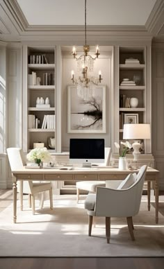 a home office with white furniture and chandelier