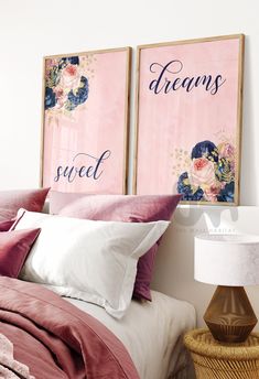 two pink posters above a bed with pillows and blankets on it's headboard