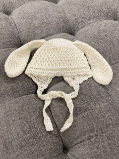 a crocheted bunny hat laying on top of a gray couch with a white headband