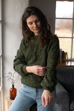 a woman standing in front of a window with her hands on her hips and looking down