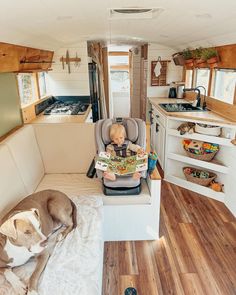 a baby sitting in a high chair next to a dog on the kitchen counter area