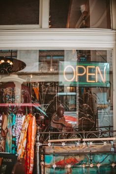 an open sign in the window of a clothing store