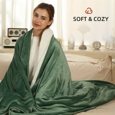 a woman wrapped in a green blanket sitting on a bed