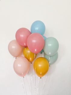 a bunch of balloons that are sitting on the ground in front of a white wall