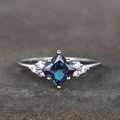 an engagement ring with a blue stone surrounded by three white diamonds on top of it