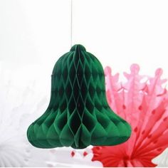 a green paper bell hanging from a string next to red and pink tissue fans in the background