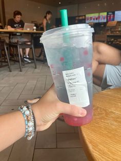 a person holding up a plastic cup filled with liquid