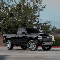 a black truck parked in front of a tree