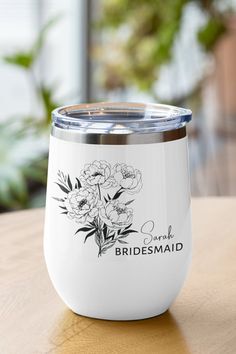 the bridesmaid wine tumbler is sitting on a table with flowers in it