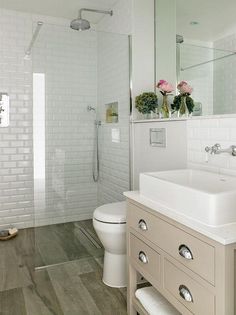 a bathroom with white tile and wood flooring