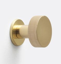 a gold door knob on a white wall with a round cover in the middle and an oval handle at the end