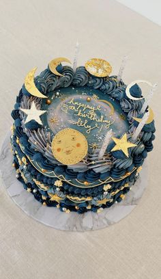 a blue and gold birthday cake with stars, moon and crescent decorations on the top