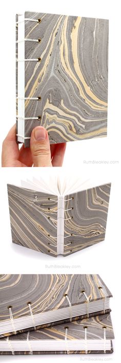 an open book that is sitting on top of a white surface with black and gold swirls