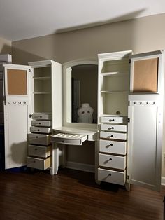 an empty dressing room with white furniture and drawers