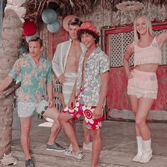 a group of men and women standing next to each other on the steps in front of a tiki hut