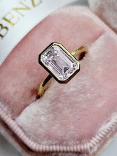 an engagement ring sitting on top of a pink velvet bag