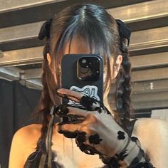 a woman taking a selfie in front of a mirror with her cell phone and hair braids