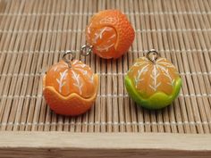 two oranges and one green apple are on a bamboo mat with white lines in the background