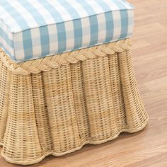 a blue and white checkered seat cushion on top of a wicker bench with wood flooring