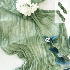 a green scarf with white flowers on it and some other items in front of it