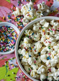 a bowl filled with sprinkles and popcorn on top of a wooden table